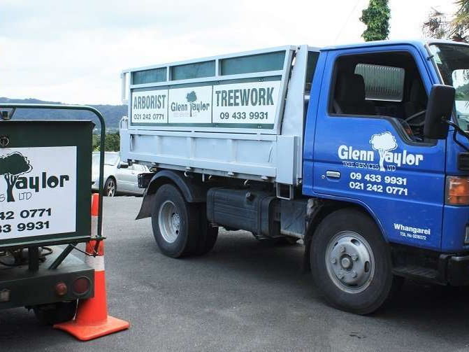 Blue Glenn Taylor Tree Services tip truck with arborist and treework signs, parked behind a road cone